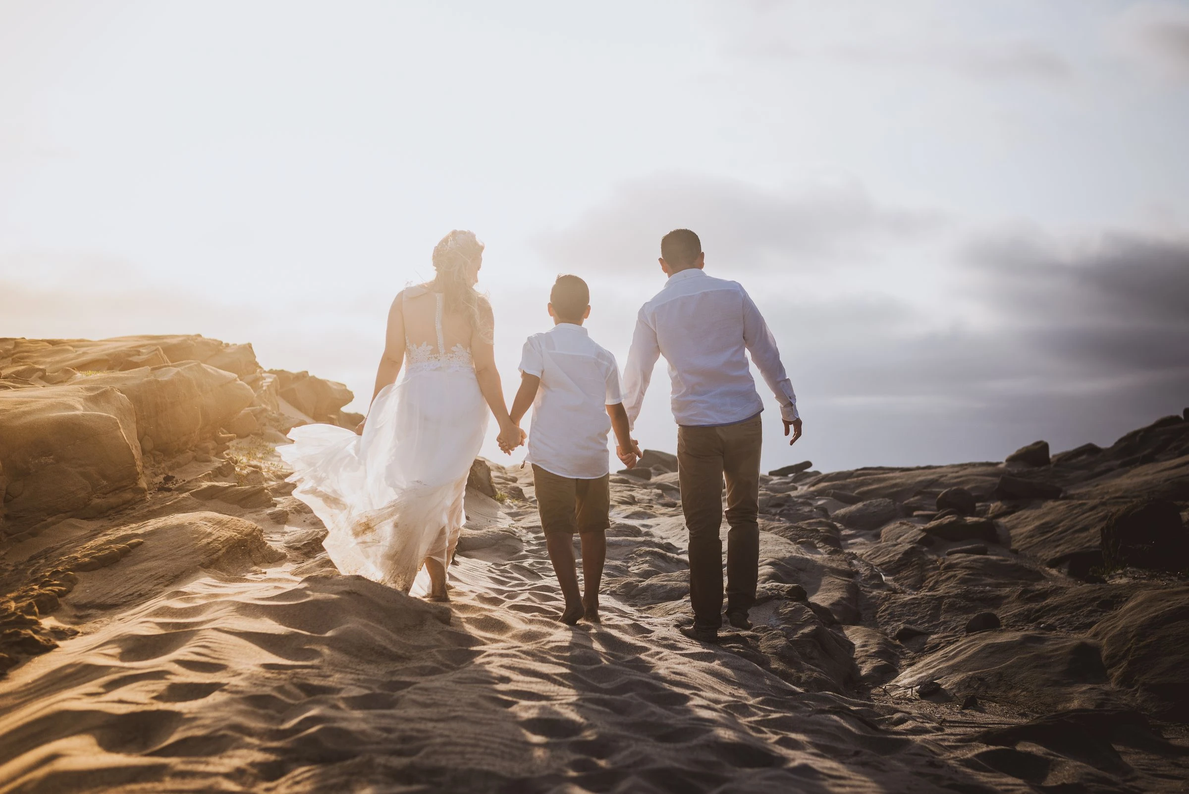 A family holding hands while walking along a beach.
